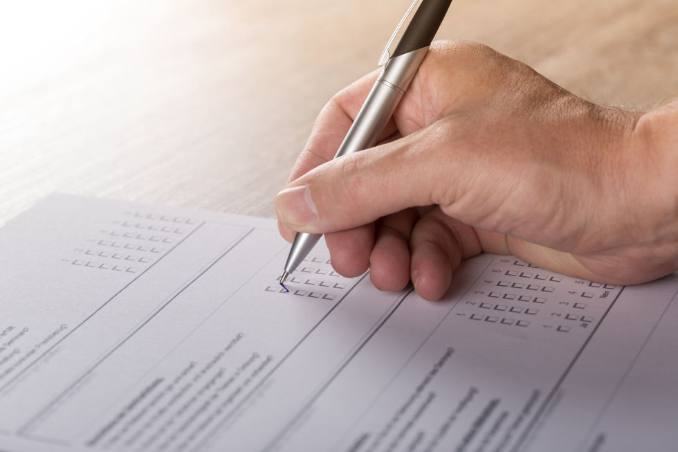 A persons hand filling out a checklist